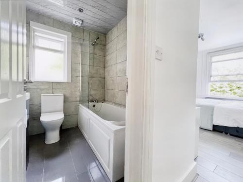 a bathroom with a toilet and a tub and a sink at Modern Room in Centrally Located Apartment - Room 4 in London