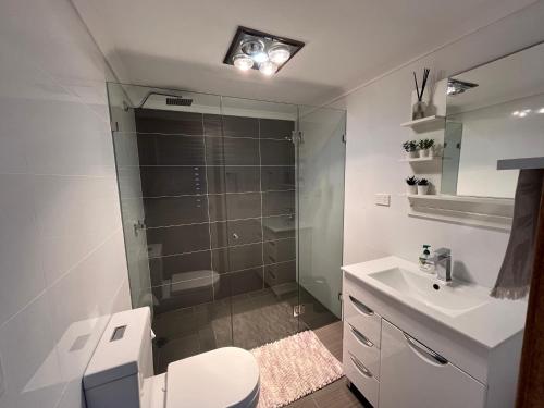 y baño con ducha, aseo y lavamanos. en Palm beach Sydney, Modern home with water view, en Palm Beach