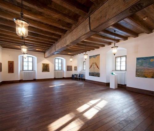 a large room with wooden floors and paintings on the walls at Sopron Monastery Hotel in Sopron