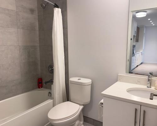 a white bathroom with a toilet and a sink at Cozy 1BR Condo w/ Insuite LDRY, Gym & Free Parking in Waterloo