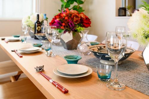 a table with glasses and plates and flowers on it at 最大12人築浅物件 南部を満喫したい方に1番のおすすめ宿 無料駐車場3台 サウスウィンドハウス in Inamine