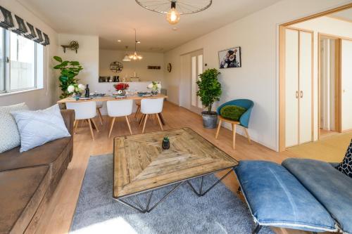a living room with a couch and a table at 最大12人築浅物件 南部を満喫したい方に1番のおすすめ宿 無料駐車場3台 サウスウィンドハウス in Inamine