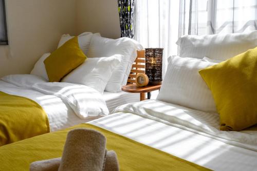 a bedroom with two beds with yellow and white pillows at 最大12人築浅物件 南部を満喫したい方に1番のおすすめ宿 無料駐車場3台 サウスウィンドハウス in Inamine
