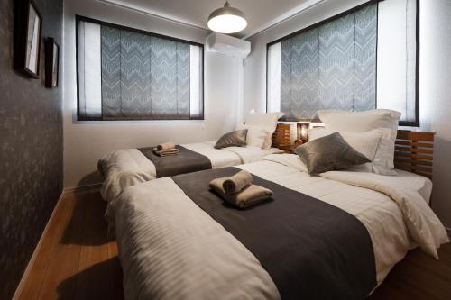 a room with three beds with towels on them at 最大12人築浅物件 南部を満喫したい方に1番のおすすめ宿 無料駐車場3台 サウスウィンドハウス in Inamine