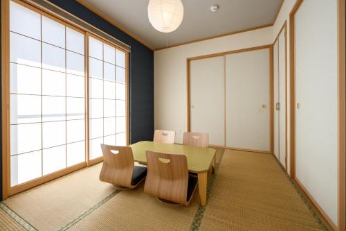 a dining room with a table and chairs and a large window at 最大12人築浅物件 南部を満喫したい方に1番のおすすめ宿 無料駐車場3台 サウスウィンドハウス in Inamine