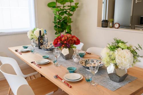 a dining room table with flowers and glasses on it at 最大12人築浅物件 南部を満喫したい方に1番のおすすめ宿 無料駐車場3台 サウスウィンドハウス in Inamine