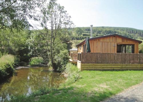 een houten hut met een rivier ervoor bij Clun Valley Lodges in Clunton