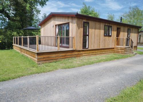een klein huis met een terras op het gras bij Clun Valley Lodges in Clunton