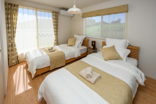 a bedroom with two beds and a window at 最大12人築浅物件 南部を満喫したい方に1番のおすすめ宿 無料駐車場3台 サウスウィンドハウス in Inamine