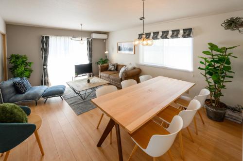 a living room with a wooden table and chairs at 最大12人築浅物件 南部を満喫したい方に1番のおすすめ宿 無料駐車場3台 サウスウィンドハウス in Inamine