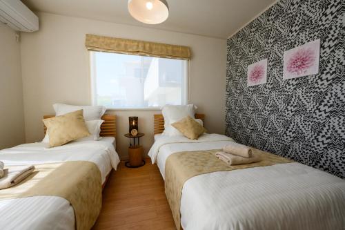 two beds in a room with a window at 最大12人築浅物件 南部を満喫したい方に1番のおすすめ宿 無料駐車場3台 サウスウィンドハウス in Inamine