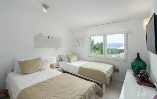 a white room with two beds and a window at Beautiful Home In Naklice With Kitchen in Gata