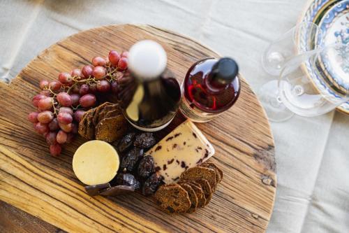 a wooden cutting board with cheese and grapes and wine at The Grove Estate in Porepunkah