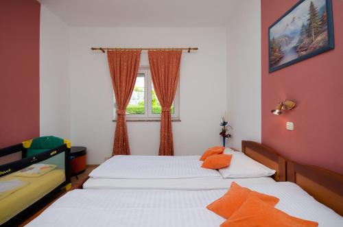 2 łóżka pojedyncze w pokoju z oknem w obiekcie Apartments Mirjana w mieście Lopar