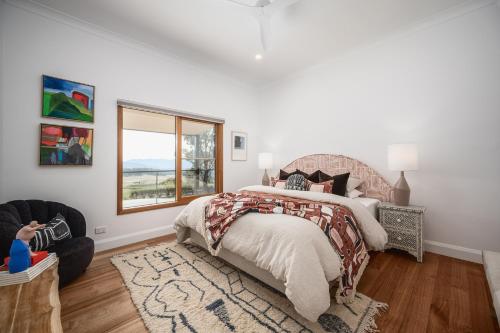a bedroom with a bed and a chair and a window at The Grove Estate in Porepunkah