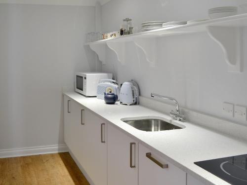 een witte keuken met een wastafel en een magnetron bij Buzzards - 8235 in Bridport