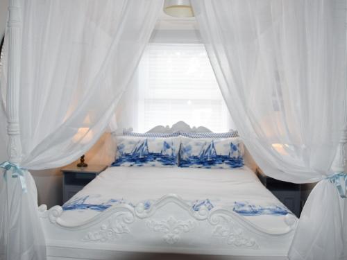 a bedroom with a blue and white bed with curtains at Buzzards - 8235 in Bridport