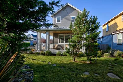 a house with a porch and a tree in the yard at Sasquatch Shore House in Ocean Shores