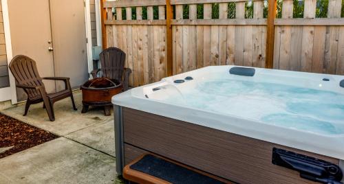 a hot tub in a backyard with two chairs and a fence at Sasquatch Shore House in Ocean Shores