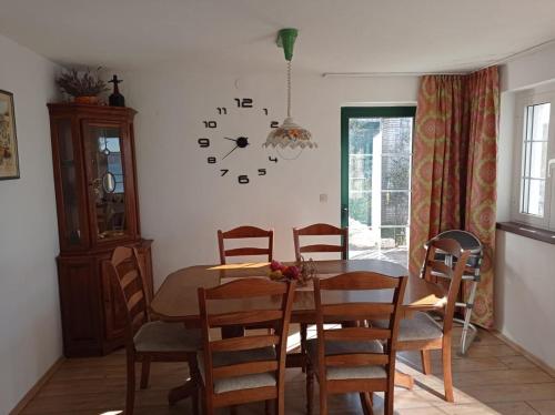 ein Esszimmer mit einem Tisch und einer Uhr an der Wand in der Unterkunft Apartment Island memories in Prvić Šepurine