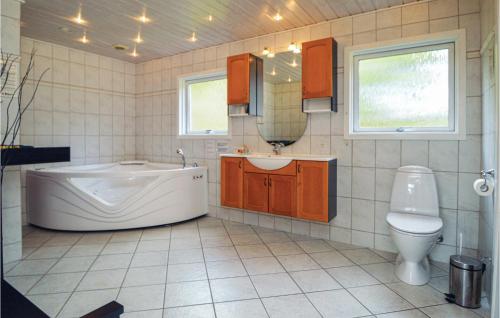 a bathroom with a tub and a sink and a toilet at Nice Home In Blvand With Kitchen in Ho