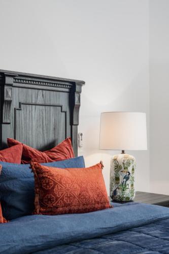 a bed with red and blue pillows and a lamp at The Grove Estate in Porepunkah