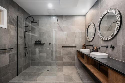 a bathroom with a shower and two sinks and a mirror at The Grove Estate in Porepunkah