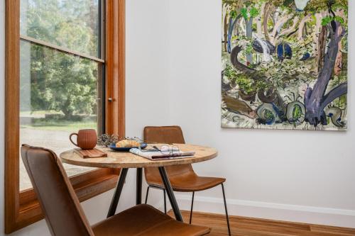 a dining room with a table and chairs and a painting at The Grove Estate in Porepunkah