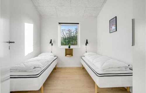 two beds in a room with white walls and a window at Nice Home In Hadsund With Sauna in Hadsund