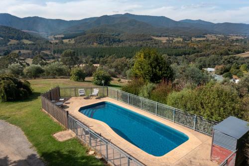 a swimming pool with a fence and mountains in the background at The Grove Estate in Porepunkah