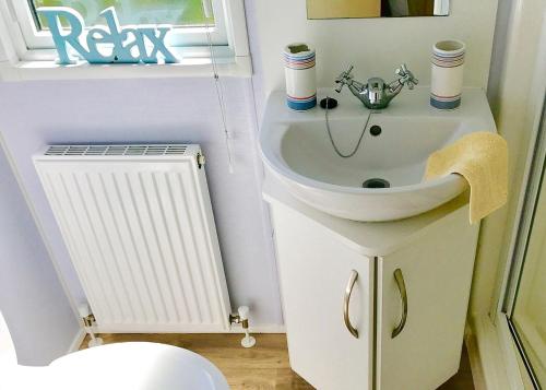 a bathroom with a sink and a toilet and a window at Mersea Island Holiday Park in East Mersea