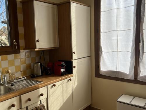 une cuisine avec des armoires blanches, un évier et une fenêtre dans l'établissement Villa 77m² près de la plage et du centre de Cabourg, avec jardin, terrasse, animaux bienvenus - FR-1-487-343, à Cabourg