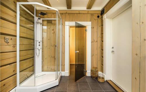 La salle de bains est pourvue d'une douche en verre et de murs en bois. dans l'établissement Lovely Home In Sjusjen With Kitchen, à Sjusjøen