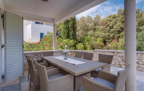 a table and chairs on a patio with a stone wall at Beautiful Home In Sveti Jakov With Kitchen in Sveti Jakov