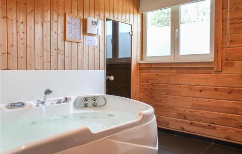 uma banheira num quarto com paredes de madeira em Lovely Home In Heel With Wifi em Heel