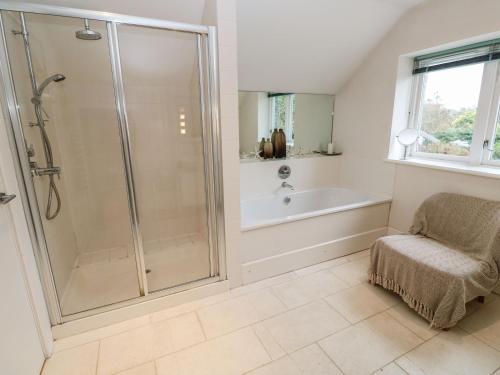a bathroom with a shower and a tub and a chair at Penarvon House in Helford