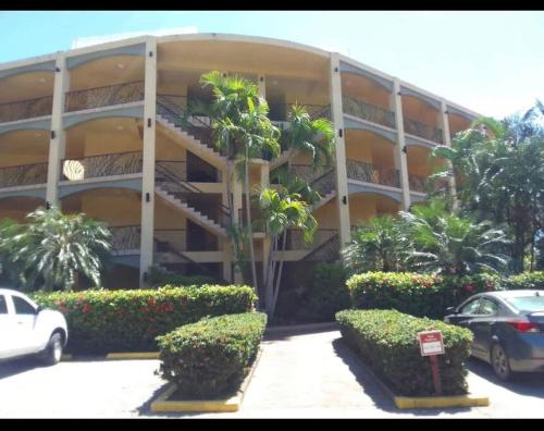 a building with palm trees in front of a parking lot at Condo Unit 131! Stay with us !!! in French Harbour