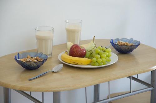a table with a plate of fruit and two glasses of milk at Iris Apartments in Minia