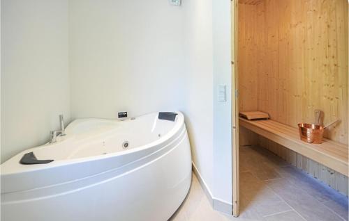 SpottrupにあるBeautiful Home In Spttrup With Saunaの木製の壁のバスルーム(白いバスタブ付)