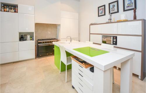 a kitchen with white cabinets and a green island at Grand Pavillion in Aubais