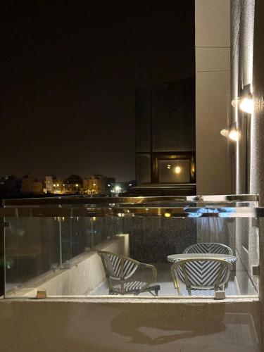 two chairs and a table on a balcony at night at منتجع اووه يامال البحري في الخيران OOh Yaa Mal in Al Khīrān
