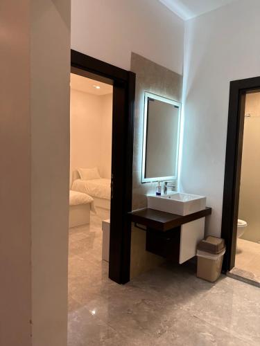 a bathroom with a sink and a mirror and a bed at منتجع اووه يامال البحري في الخيران OOh Yaa Mal in Al Khīrān
