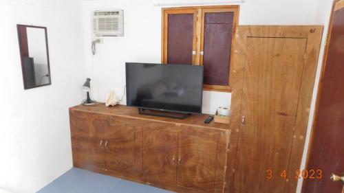 telewizor siedzący na drewnianym komodzie w obiekcie Cute Quiet Private Room w own Kitchen, CR, Porch w Panglao City