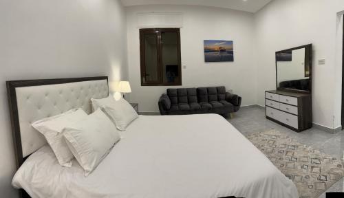 a bedroom with a large white bed and a couch at منتجع اووه يامال البحري في الخيران OOh Yaa Mal in Al Khīrān