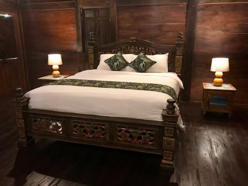a bedroom with a large bed with two lamps at Alas Arum Ecolodge in Tabanan