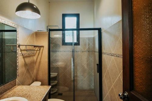 uma casa de banho com um chuveiro e uma porta de vidro em Exclusive Beachfront House w/ Pool & Saltwater Tub em Catmon