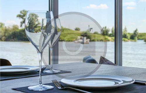 a table with two wine glasses and plates on it at Houseboat Waterlelie in Ohé en Laak
