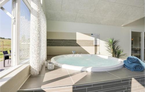 VejbyにあるCozy Home In Vejby With Indoor Swimming Poolの大きな窓付きのバスルーム(大きなバスタブ付)