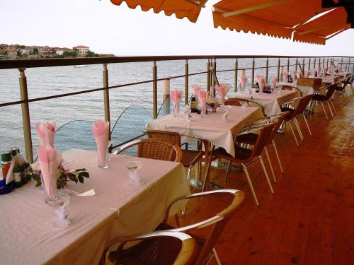 eine Reihe von Tischen auf einem Kreuzfahrtschiff mit rosafarbener Dekoration in der Unterkunft Hotel Parnasse in Sozopol