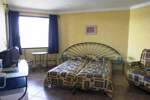 a bedroom with a bed and a table and a tv at Hotel Parnasse in Sozopol